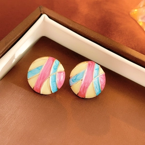 Close-up of vintage flower enamel earrings in pink and blue on a soft white display