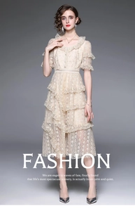 Détail d'une robe en dentelle beige avec volants superposés et broderies raffinées
