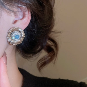 Detail of silver vintage flower stud earrings with blue zircon on model ear