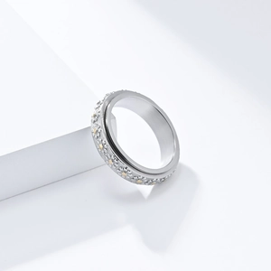 Rotating stainless steel daisy ring with gold accents on a minimalist geometric pedestal