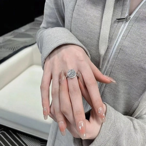 Macro shot of oval cut moissanite ring with halo setting on a manicured model hand