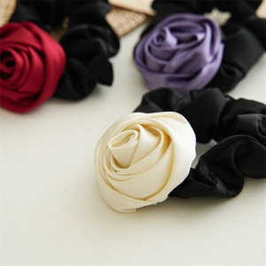 Macro shot of satin rose hair scrunchies in red, purple, and cream white colors