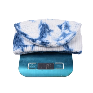 Dettaglio del berretto in maglia tie-dye da 83g su bilancia con trama a coste