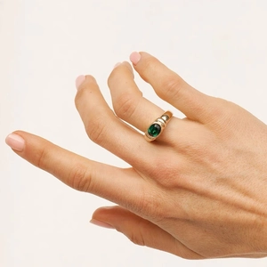 Detailed view of a wide gold-plated ring featuring an oval emerald green zircon stone