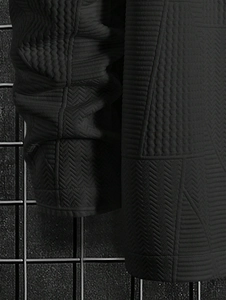 Detail of black jacket showing jacquard herringbone texture and stitched panel design