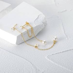 Detail of S925 silver gold tassels with white pearls on a minimalist stone background