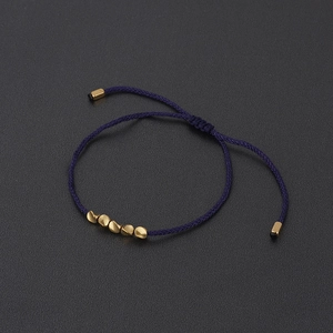 Detailed shot of dark blue braided cord bracelet with five gold irregular shaped beads