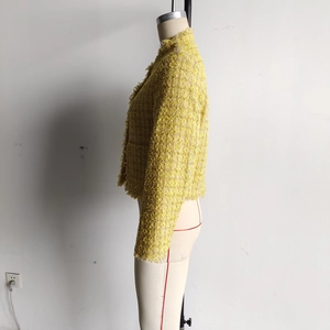 Detail of yellow tweed jacket side view showing textured fabric and fringe trim