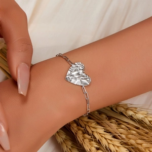 Close-up of silver heart bracelet with hammered texture on a model's wrist