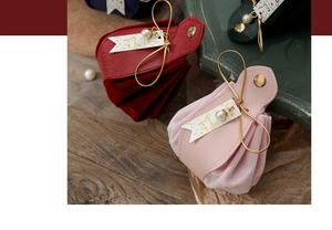 Detail of velvet and faux leather wedding favor bags with pearls and bows in multiple colors