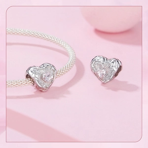 Macro shot of silver heart charm with cubic zirconia on a mesh bracelet detail