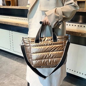Fashionable gold quilted puffer tote bag shown on model with adjustable black strap