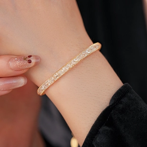 Vue détaillée d'un bracelet en maille dorée rempli de cristaux de zircon sur le poignet