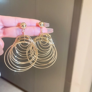 Detailed view of layered gold concentric hoop earrings with spherical studs and metallic finish