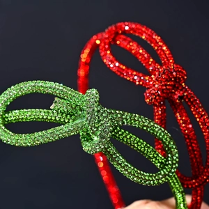 Close-up of red and green rhinestone bow headbands with shiny metallic crystals