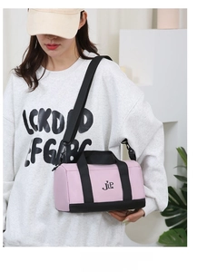 Detail of pink and black nylon cylinder crossbody bag worn by model in a casual setting
