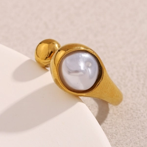 Macro shot of 18K gold plated snake head ring with large white pearl on textured background