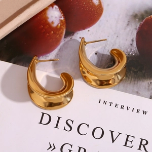 Gros plan de boucles d'oreilles C dorées à l'or 18K avec finition miroir sur fond de texte
