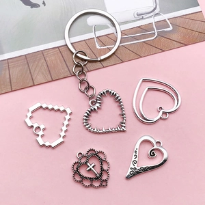 Detailed set of silver alloy heart pendants and keychains on a soft pink background