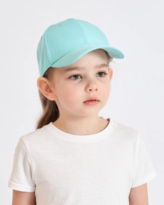 Close-up of a child wearing a mint green baseball cap against a white background