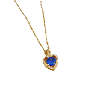 Titanium steel gold heart necklace with blue center stone and crystals on white background