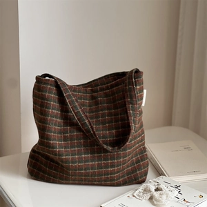 Detail of vintage wool plaid shoulder bag with stripes, lace accessory and book