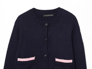 Detail of navy knit cardigan featuring pink contrast trim on pockets and dark buttons