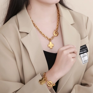 Detail showing 18K gold cross pendant necklace and bracelet set with OT toggle closure