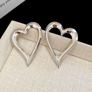 Detailed macro view of polished silver heart earrings on a textured display pad
