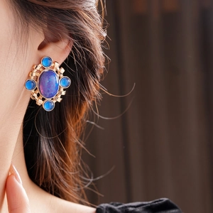 Vintage luxury gold earrings with blue opal-style stones shown on a model