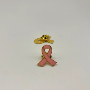 Close-up of pink ribbon enamel pins showing gold trim and butterfly clutch backing
