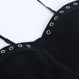 Detalle del top de PU negro que muestra ojales plateados y tirantes finos ajustables