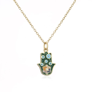 Makro-Detail der vergoldeten Hamsa-Kette mit grüner Emaille und blauen Schutzaugen