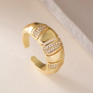 Luxuriöser breiter goldener Ring mit Zirkonia-Inlay auf strukturiertem Steinhintergrund