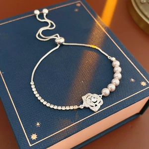 Gros plan d'un bracelet fleur en argent avec perles blanches sur écrin bleu chic