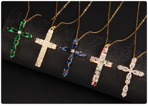 Detail view of five gold-plated cross necklaces featuring colorful cubic zirconia on black rolls