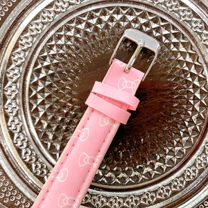 Detail of pink faux leather watch strap with white bow patterns and silver buckle