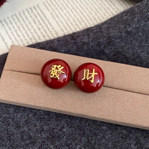 Gros plan de boucles d'oreilles rouges et dorées avec caractères chinois de prospérité