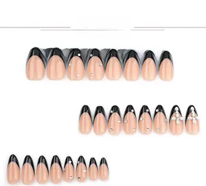 Detail of almond press-on nails featuring black French tips with silver cross and rhinestones