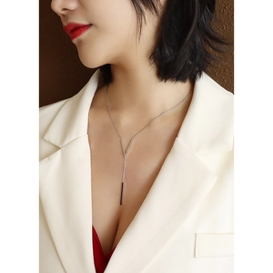 Elegant silver V-shaped necklace with vertical bar pendant worn with a white blazer