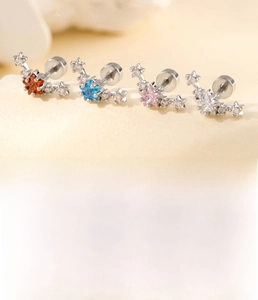 Detail of star-shaped titanium steel ear studs with colored zircon and screw flat back