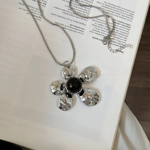 Silver flower pendant necklace with hammered metal texture and black bead on snake chain