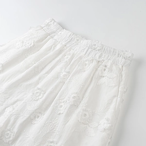 Detailed view of elastic waistband and intricate white floral embroidery on cotton fabric