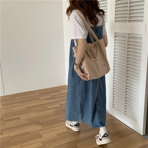 Detalle de un bolso tote de lona beige minimalista con un vestido midi vaquero azul