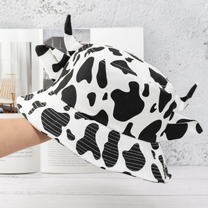 Detail view of a cow print bucket hat with cute 3D horns and ears decoration