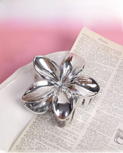Macro shot of silver metallic flower hair claw clip with a polished glossy finish