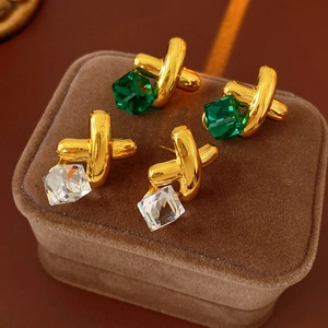 Detailed view of vintage gold-tone cross earrings with green and clear crystal cubes