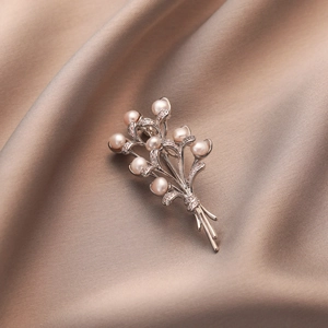 Detailed view of silver wheat brooch with freshwater pearls on silk fabric