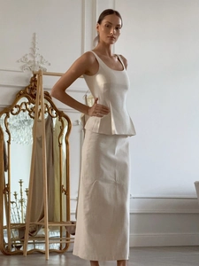 Ensemble chic deux pièces avec haut à basque blanc et jupe longue dans un décor élégant