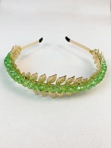 Detailed view of handmade leaf headband with gold metal leaves and green crystal beads
